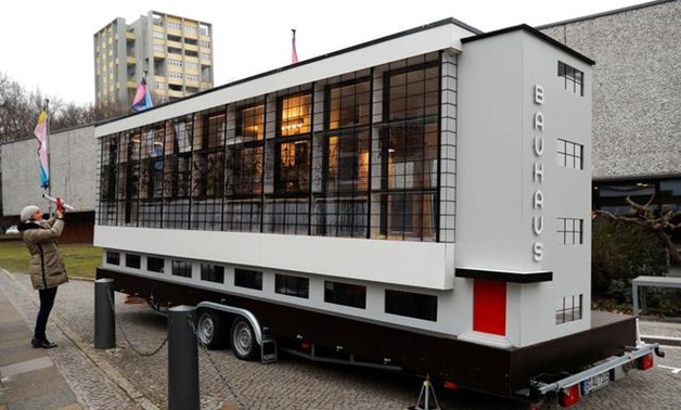 A woman takes a picture of a tiny house called "Wohnmaschine" (living machine) constructed from a bus and designed by architect Van Bo Le-Mentzel in a version of the Bauhaus school building in Dessau to mark 100th anniversary of Bauhaus in Berlin, Germany