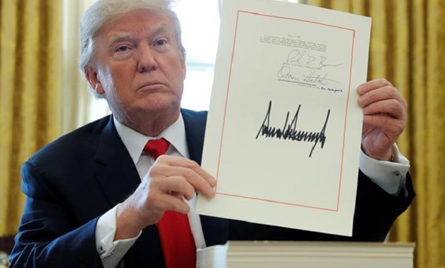 FILE PHOTO: U.S. President Donald Trump displays his signature after signing the $1.5 trillion tax overhaul plan along with a short-term government spending bill in the Oval Office of the White House in Washington, U.S., December 22, 2017. REUTERS/Jonatha