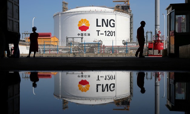 FILE PHOTO - A liquified natural gas (LNG) storage tank and workers are reflected in a puddle at PetroChina's receiving terminal-September 4, 2018. REUTERS/Stringer
