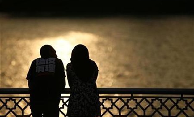 A couple watch a sunset near a lake in Putrajaya December 22, 2008. REUTERS/Bazuki Muhammad