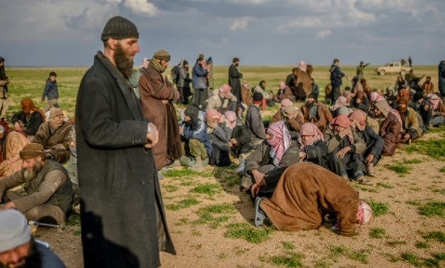 A man prays as men suspected of being Islamic State (IS) fighters wait to be searched by members of the Kurdish-led Syrian Democratic Forces (SDF) in Syria's northern Deir Ezzor province, on February 22, 2019 AFP/File
