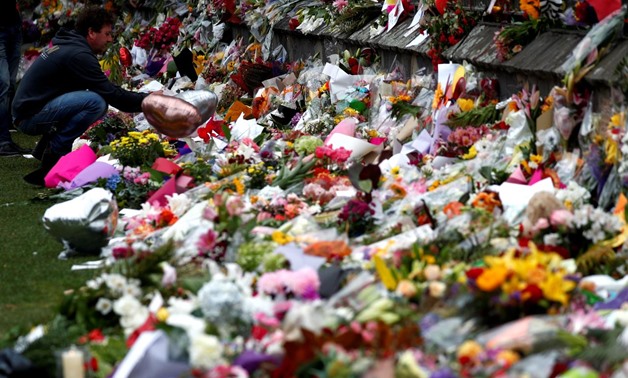 A man places flowers at a memorial site for victims of the mosque shootings at the Botanic Gardens in Christchurch, New Zealand, March 18, 2019. REUTERS/Edgar Su
