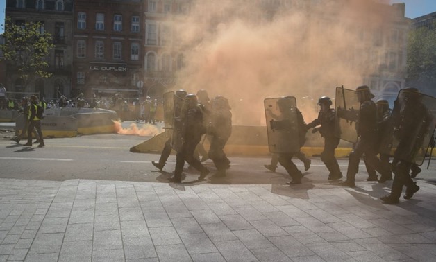 Pascal Pavani, AFP | Anti-riot police officers walk amid smoke as "Yellow vests" protesters take to the streets for the 22nd consecutive Saturday, on April 13, 2019, in Toulouse.
