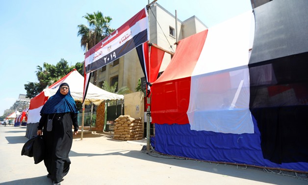 An Egyptian woman walks in front of a polling station covered from outside by Egyptian flags, during the preparations for the upcoming referendum on constitutional amendments in Cairo, Egypt April 18, 2019. REUTERS/Amr Abdallah Dalsh
