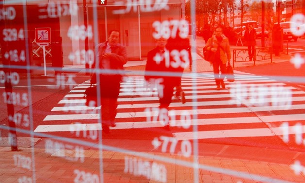 FILE PHOTO - Pedestrians are reflected on an electronic board showing stock prices outside a brokerage in Tokyo, Japan December 27, 2018. REUTERS/Kim Kyung-Hoon
