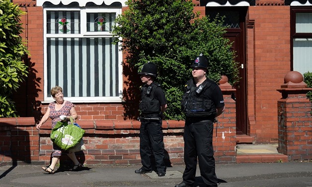 Police officers as they stand on duty on Dorset Avenue in Moss Side, Manchester -AFP