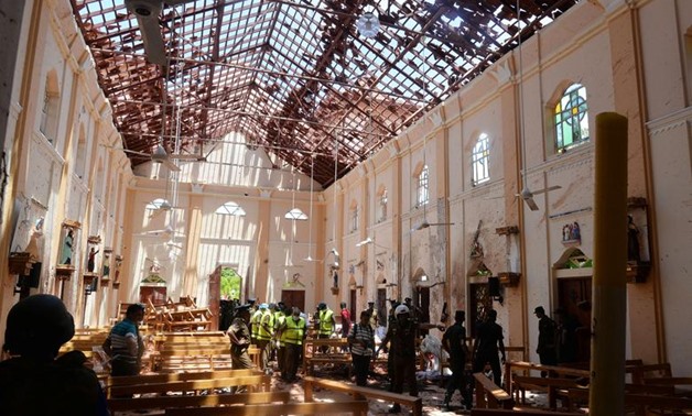 Crime scene officials inspect the site of a bomb blast inside a church in Negombo - Reuters