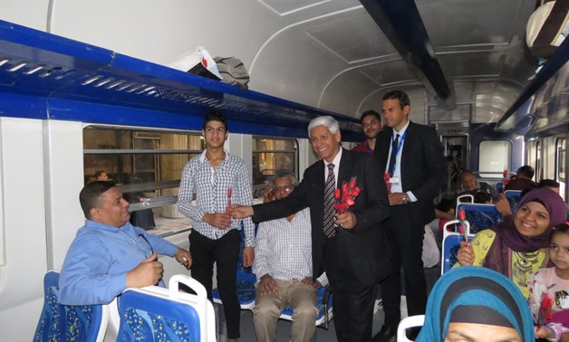 The Public Relations manager of the Egyptian National Railway and commuters pose for a photo at Cairo-Alexandria train after distributing candy and flowers to train commuters - Egypt Today/ Azoz Al-Dib