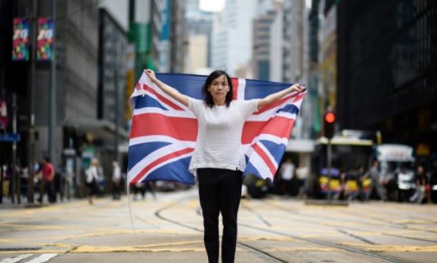 Designer Alice Lai, 39, holds a British Union Jack flag on a main road in Hong Kong. Almost 20 years after the city was handed back to China