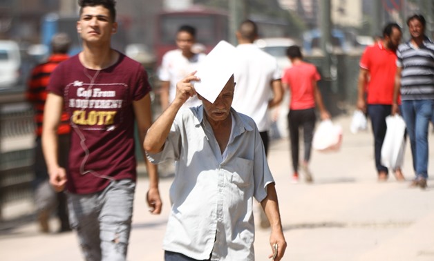 FILE- An Egyptian man covers his head with a paper to avoid the sun rays amid high temperature in Cairo- the photo was taken on August 3, 2018- Egypt Today/Mohamed Fawzy