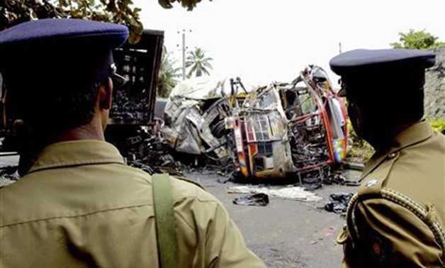 Police officers look at the wreckage of a passenger bus in Colombo April 10, 2007. REUTERS/Buddhika Weerasinghe

