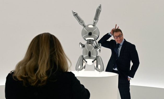 Timothy A. Clary, AFP | A man poses next to Jeff Koons' "Rabbit" at Christie's New York press preview on May 3, 2019.