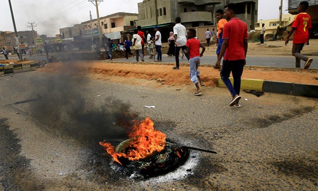 Sudanese protesters walk past burning tyres used to erect a barricade on a street, demanding that the country's Transitional Military Council handover power to civilians, in Khartoum, Sudan June 4, 2019. REUTERS/Stringer
