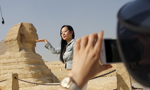 A Chinese tourist poses for a photo in front of the Sphinx at the Giza Pyramids on the outskirts of Cairo, Egypt, March 2, 2016 - REUTERS/Amr Abdallah Dalsh