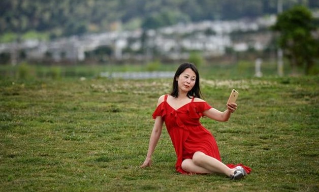 A woman takes selfies with a mobile phone near Erhai Lake in Dali Bai Autonomous Prefecture, Yunnan province, China June 15, 2019. REUTERS/Tingshu Wang
