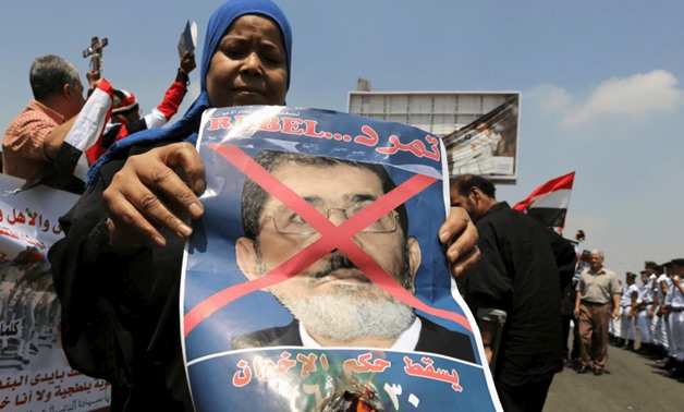 A woman burns a portrait of ousted President Mohamed Morsi at the funeral of Egyptian public prosecutor Hisham Barakat, on the second anniversary of the June 30 protests, in Cairo, Egypt, June 30, 2015. 