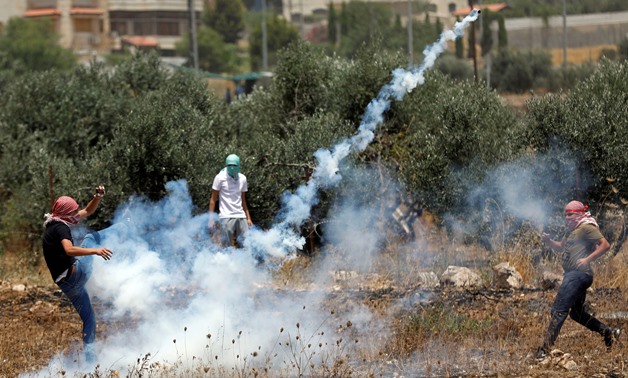 A Palestinian demonstrator kicks a tear gas canister fired by Israeli forces during a protest over the death of a Palestinian prisoner in an Israeli jail, near the Jewish settlement of Beit El, in the Israeli-occupied West Bank July 17, 2019. REUTERS/Moha