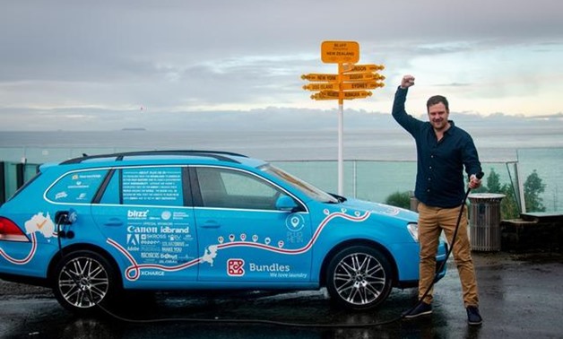 Dutchman Wiebe Wakker holds a charging cable as he poses with his electric vehicle, the Blue Bandit, after travelling 34 countries to reach Bluff, New Zealand's most southern tip, in this handout photo released July 19, 2019. Wiebe Wakker/Handout via REUT