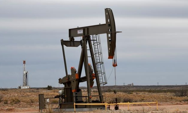 FILE PHOTO: A pump jack operates in front of a drilling rig owned by Exxon near Carlsbad, New Mexico, U.S. February 11, 2019. Nick Oxford/File Photo