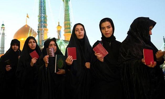 Iranian women hold their identity cards as they queue to vote in May presidential election at the Massoumeh shrine in the Shiite Muslim holy city of Qom - AFP