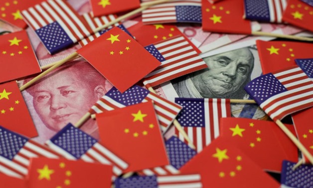 A U.S. dollar banknote featuring American founding father Benjamin Franklin and a China's yuan banknote featuring late Chinese chairman Mao Zedong are seen among U.S. and Chinese flags in this illustration picture taken May 20, 2019. REUTERS/Jason Lee/Ill