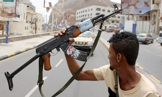 FILE PHOTO: A member of Yemen's southern separatist holds his weapon with a picture of Muneer al-Yafee during a funeral of Brigadier General Muneer al-Yafee and his comrades killed in a Houthi missile attack, in Aden, Yemen, August 7, 2019. REUTERS/Fawaz 
