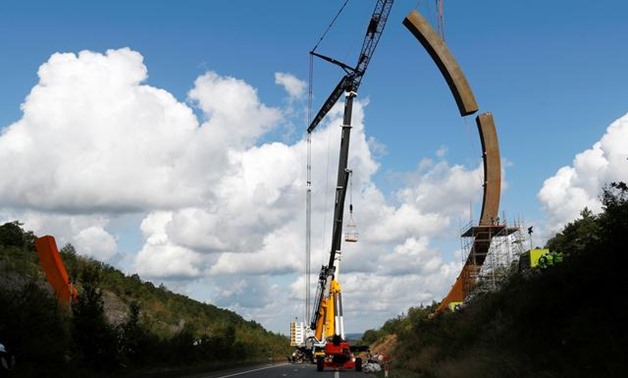 A crane is used to put the last piece of the Arc Majeur, a 60-meter arch designed by French artist Bernar Venet and installed on the E411 highway in Lavaux-Sainte-Anne, Belgium, August 13, 2019. REUTERS/Francois Lenoir
