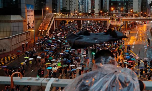 A person holding a broken umbrella observes anti-extradition bill protesters marching to demand democracy and political reforms, in Hong Kong, China August 18, 2019. REUTERS/Tyrone Siu

