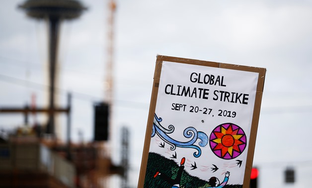 A tech worker holds a climate strike sign with the Space Needle seen in the background during a Climate Strike walkout and march in Seattle, Washington, U.S. September 20, 2019. REUTERS/Lindsey Wasson