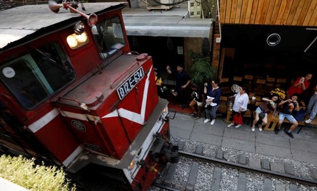 Tourists take photos as a train comes down the track along a street in the Old Quarter of Hanoi, Vietnam September 28, 2019. Picture taken September 28, 2019. REUTERS/Kham
