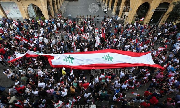 Demonstrators carry national flags during an anti-government protest in downtown Beirut, Lebanon October 20, 2019. REUTERS/Ali Hashisho
