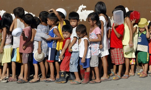 Children queue for free porridge at a local government feeding program in Tondo, Manila, Oct. 29, 2011. REUTERS/Erik De Castro

