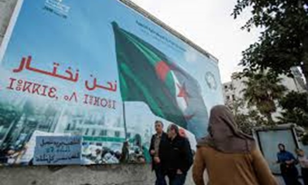 People walk past a campaign poster for presidential election in Algiers, Algeria November 2, 2019. REUTERS/Ramzi Boudina
