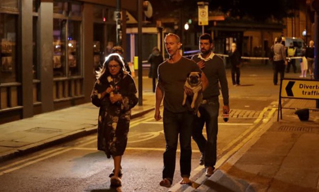 A man carries a dog with a woman wearing a dressing gown after an attack in London, Sunday, June 4, 2017. Terrorism struck at the heart of London, police said Sunday, after a vehicle veered off the road and mowed down pedestrians on London Bridge and witn