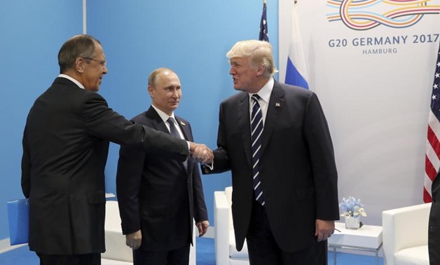 U.S. President Donald Trump (R) shakes hands with Russian Foreign Minister Sergei Lavrov as Russian President Vladimir Putin stands nearby during a meeting on the sidelines of the G20 summit in Hamburg, Germany July 7, 2017 Sputnik/Mikhail Klimentyev/Krem