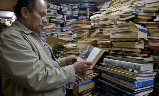Jose Alberto Gutierrez checks books stacked in his library on the first floor of his house in Bogota May 18, 2017. — AFP pic