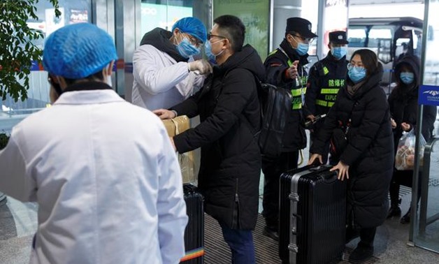 A medical official takes the body temperature of a man at the departure hall of the airport in Changsha, Hunan Province, as the country is hit by an outbreak of a new coronavirus, China, January 27, 2020. REUTERS/Thomas Peter
