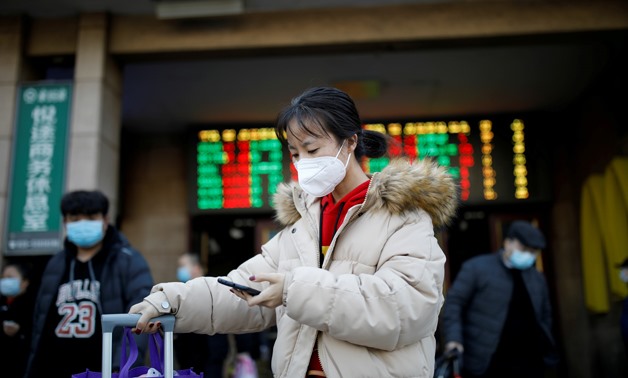 A woman wearing a face mask uses her cellphone as she walks outside Beijing Railway Station as the country is hit by an outbreak of the new coronavirus, in Beijing, China January 30, 2020. REUTERS/Carlos Garcia Rawlins