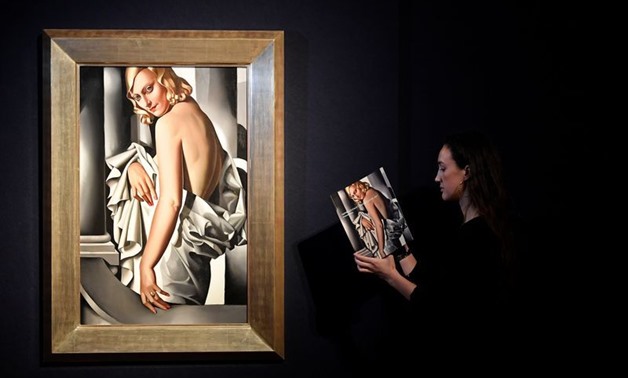 An employee poses as she views a sales catalogue next to 'Portrait de Marjorie Ferry' by Tamara de Lempecka ahead of Impressionist, Modernist and Surreal sales at Christie's auction house, London, Britain, January 30, 2020. REUTERS/Toby Melville

