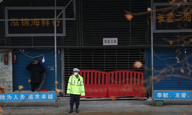 FILE PHOTO: A police officer wearing a mask stands in front of the closed seafood market in Wuhan, Hubei province, China January 10, 2020. REUTERS/Stringer