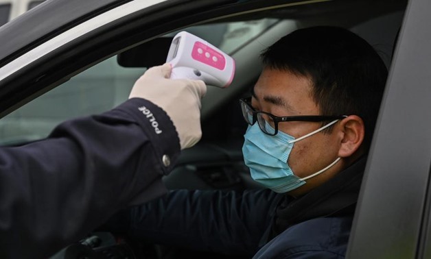 A police officer takes the temperature of a driver at a checkpoint on a street on the outskirts of Wuhan in China’s central Hubei province on January 27, 2020, amid a deadly virus outbreak which began in the city. Photo: AFP/Hector Retamal
