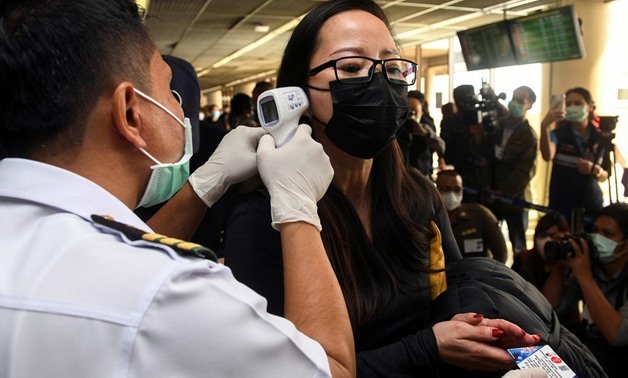 A health worker uses an infrared thermometer to check the temperature of a tourist who arrives at Bangkok's Don Mueang Airport, Thailand, January 25, 2020. REUTERS/Panumas Sanguanwong