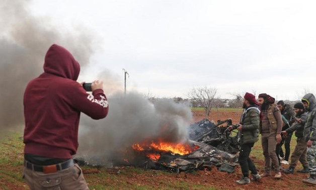 Syrian opposition fighters gather around the burning remains of a downed military helicopter. (AFP)
