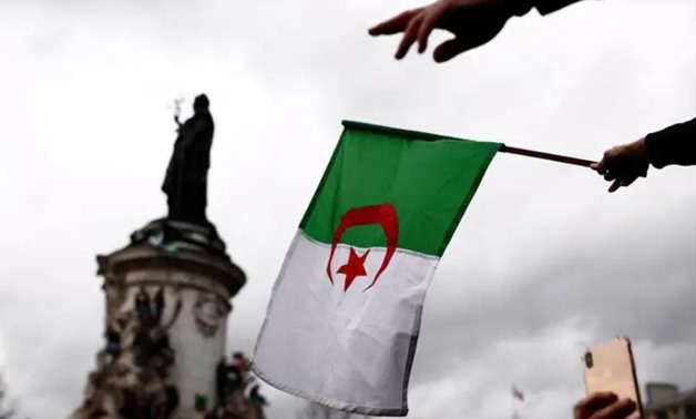 FILE - An Algerian protester waves the national flag - Reuters