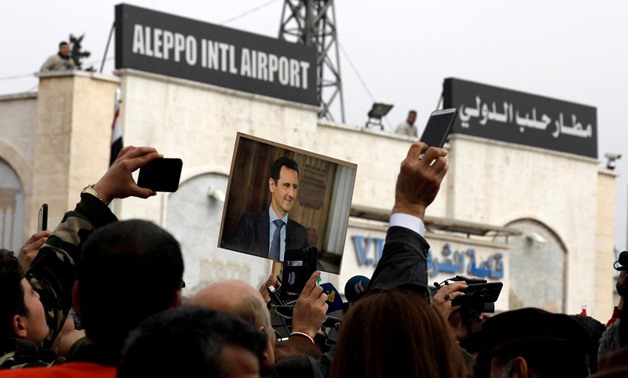 People hold up a picture of Syria's President Bashar al-Assad at Aleppo international airport, after the airport was reopened for the first time in years, Syria February 19, 2020. REUTERS/Omar Sanadiki