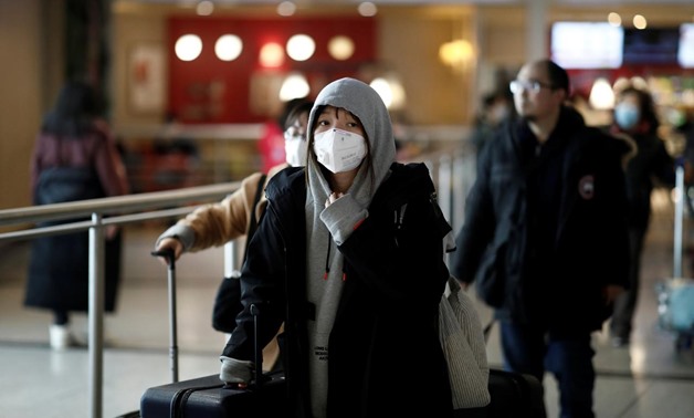 FILE PHOTO: Tourists from an Air China flight from Beijing wear protective masks as they arrive at Charles de Gaulle airport in Paris, France, January 26, 2020. REUTERS/Benoit Tessier