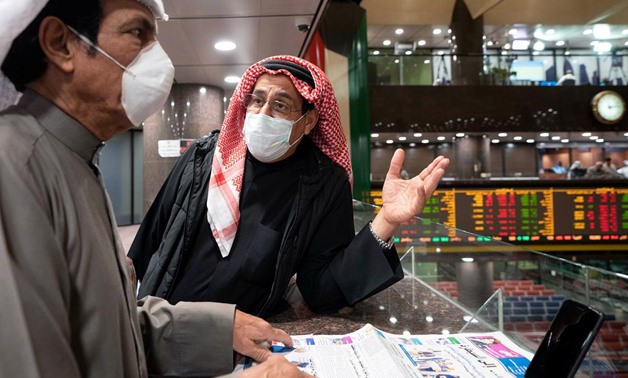 Kuwaiti traders wear protective face masks, following the outbreak of the new coronavirus, as they stand on the upper floor since the lower main hall is closed to traders at the Kuwait Boursa stock market trading in Kuwait city, Kuwait March 1, 2020. REUT