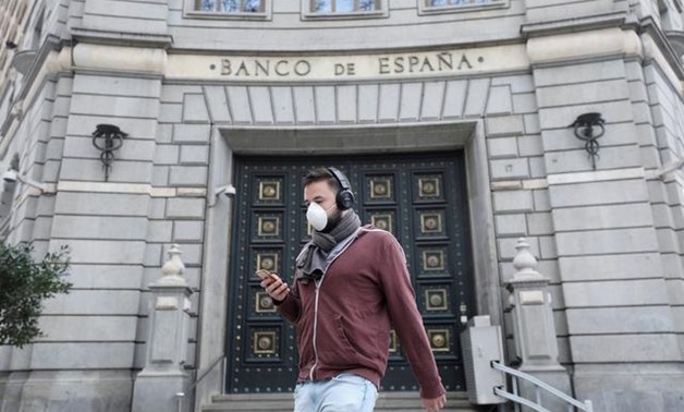 FILE PHOTO: A man wears a protective face mask as he walks past Banco de Espana (Bank of Spain), amidst concerns over coronavirus outbreak, in Barcelona, Spain March 14, 2020. REUTERS/Nacho Doce/File Photo