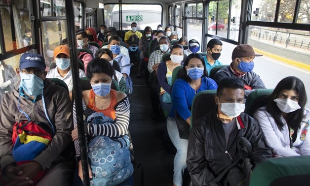 People wearing protective masks as a precaution against the spread of the new coronavirus travel on a bus in Caracas, Venezuela, Tuesday, March 17, 2020. President Nicolas Maduro ordered citizens to stay home, and to wear a mask in public under a quaranti