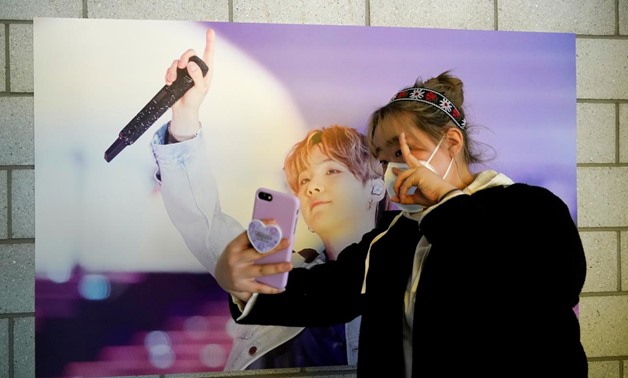 Im Yu-mi, fan of K-pop boy band BTS, takes a selfie at a cafe decorated with photos and merchandise of them, in Seoul, South Korea, March 13, 2020. Picture taken March 13, 2020. REUTERS/Kim Hong-Ji